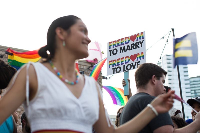 Laila Flores, left, celebrates as Chip O' Kelly, partially seen, holds a sign in downtown Atlanta following the Supreme Court's ruling that made gay marriage constitutional across the nation, Friday, June 26, 2015. (BRANDEN CAMP/AJC FILE PHOTO)