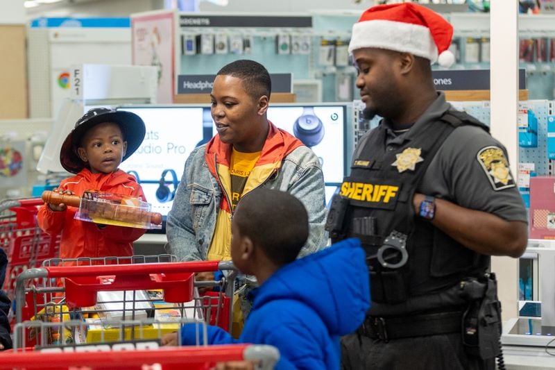 Sheriff T Williams acts as a "shopping buddy" for a family during the Shop With The Sheriff event at Target at Atlantic Station on Saturday, December 9, 2023. (Steve Schaefer/steve.schaefer@ajc.com)