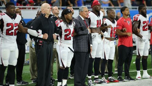 Falcons coach Dan Quinn and team owner Arthur Blank join arms with the players during the playing of the National Anthem prior to Sunday's game at Detroit. (Leon Halip/Getty Images)