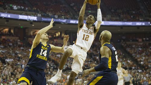 Texas Longhorns guard Kerwin Roach II (12) shoots and scores over West Virginia Mountaineers guard Chase Harler (14) and West Virginia Mountaineers guard Jevon Carter (2) in the firs half of the game. Texas wins against West Virginia 87-79 in the NCAA Game on Saturday, March 3, 2018.  RICARDO B. BRAZZIELL / AMERICAN-STATESMAN