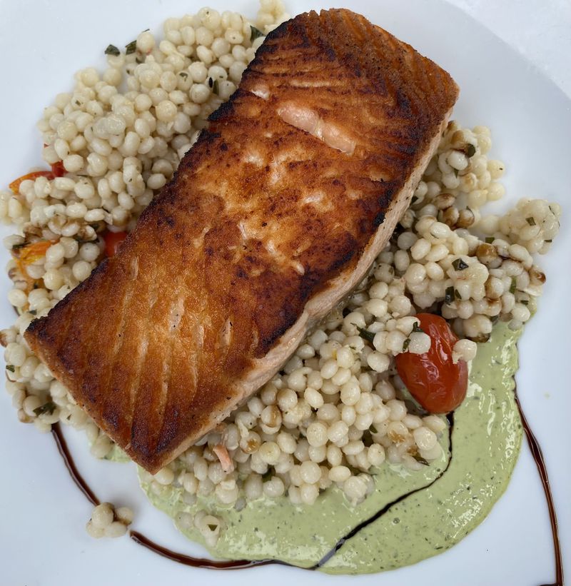 Pan-seared Atlantic salmon is among the few large plates available on the limited menu at City Winery. The dish comes with Israeli couscous, blistered cherry tomatoes and a green goddess dressing. (Ligaya Figueras / ligaya.figueras@ajc.com)