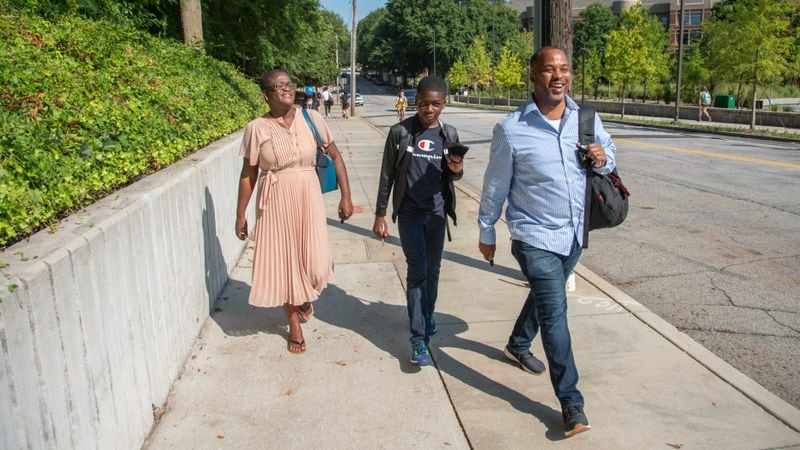 Thirteen year-old Georgia Tech student Caleb Anderson, center, walks on campus for his first day of school on Monday, Aug. 23, 2021 with his mother, Claire, to the left, and father, Kobi, on the right. PHOTO CREDIT: GEORGIA TECH.