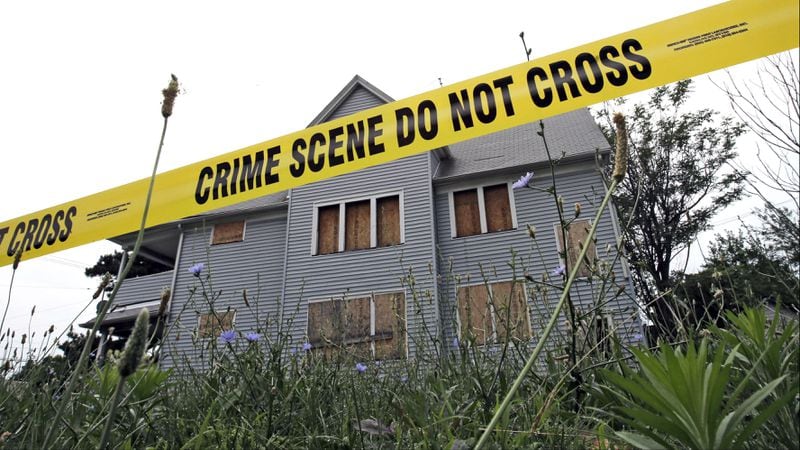 Crime scene tape cordons off a boarded-up home July 22, 2013, in an area where the bodies of three slain women were found in garbage bags in East Cleveland, Ohio. The mother of convicted serial killer Michael Madison, who was convicted in 2016 of the women's murders, was fatally stabbed to death in her home Saturday, June 22, 2019. Diane Madison's grandson has been charged in her killing and the stabbing of three of her young grandchildren.