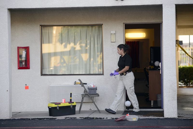 An Albuquerque Police Department officer collects evidence after a shooting that left a man dead and another injured during what police say was an altercation between the on June 30, 2015, at a Motel 6. 