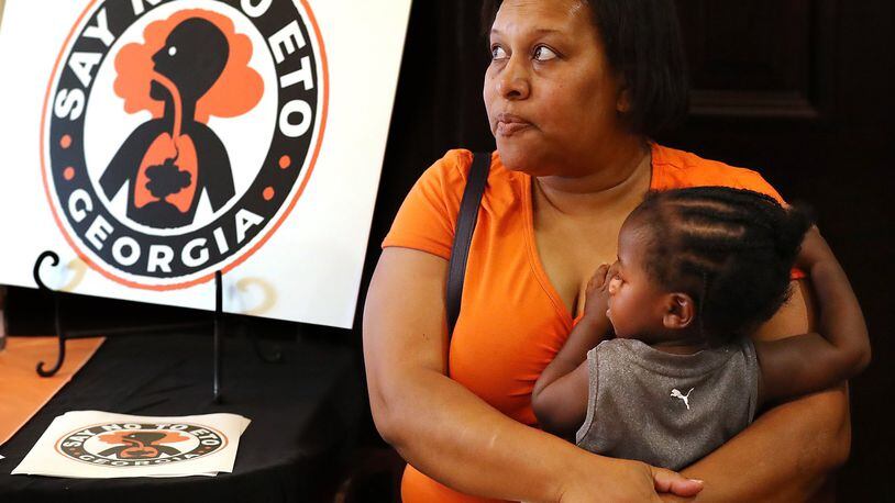 Covington resident Denise Williams holds her 1-year-old godson Davion Petty while attending the Town Hall presentation on ethylene oxide gas from the nearby Becton Dickinson plant. Curtis Compton/ccompton@ajc.com