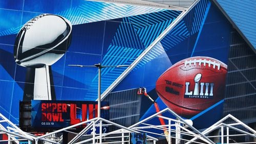 Workers use a lift to install a Super Bowl LIII wrap on the outside of Mercedes-Benz Stadium as it is transformed for the big game. Several people were indicted related to selling fake tickets to previous Super Bowl games. Curtis Compton/ccompton@ajc.com
