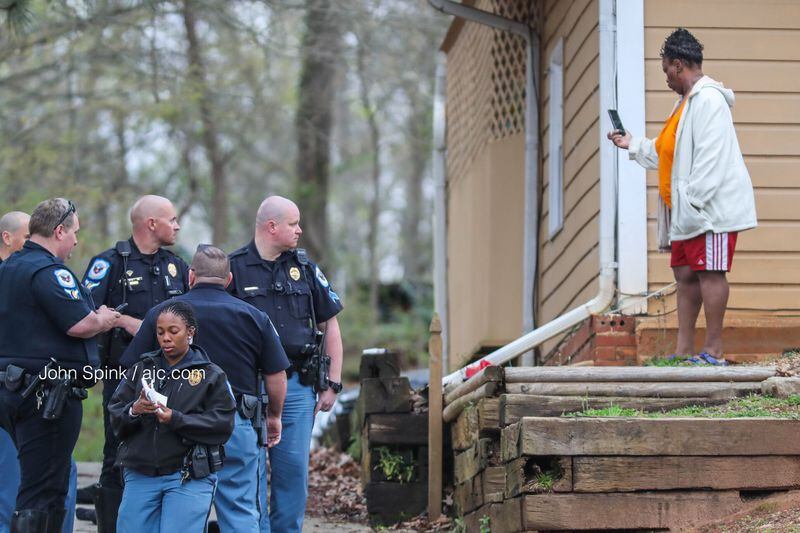A resident takes a cellphone photo of Cobb County investigators as they process evidence at her home Tuesday morning. The woman called 911 after a man showed up on her back porch with gunshot wounds. 