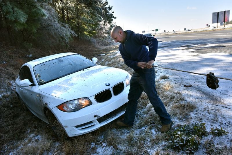 January 7, 2017 Lawrenceville - Gabriel Suarez with J & S Towing Service prepares the vehicle for towing from a difficult position alongside I-85 northbound near Old Peachtree Road exit in Gwinnett County on Saturday, January 7, 2017. Snow fell in parts of Georgia on Friday night, but much of metro Atlanta got very little or no snow at all. Still, many areas Saturday are facing icy conditions on the roads. There is a danger of slick conditions on bridges and overpasses, Channel 2 Action News meteorologist Karen Minton said.  HYOSUB SHIN / HSHIN@AJC.COM