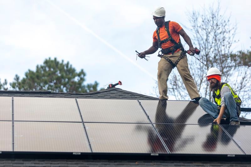 Joe McClain, right, and Mike Harris, left, installers for Creative Solar USA, install solar panels on a home in Ball Ground, Ga., Dec. 17, 2021.