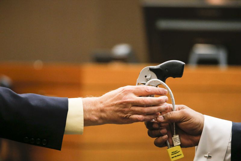 04/13/2018 -- Atlanta, GA - Criminal scene analyst Ross Martin Gardner, left, hands the gun used in the shooting of Diane McIver back to Fulton County Chief Assistant District Attorney Clint Rucker, right, during the nineteenth day of trial for Tex McIver before Fulton County Chief Judge Robert McBurney, Friday, April 13, 2018. ALYSSA POINTER/ALYSSA.POINTER@AJC.COM