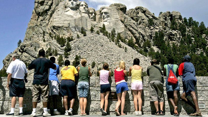 Visitors watch workers pressure-wash the granite faces of George Washington (from left), Thomas Jefferson, Theodore Roosevelt and Abraham Lincoln at Mount Rushmore National Memorial in South Dakota. (Charlie Riedel / AP file)