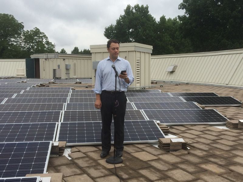 Jason Carter makes remarks Tuesday morning against a backdrop of some of the 324 solar panels now installed on the roof of the Jimmy Carter Presidential Library and Museum in Atlanta.  Photo by Jill Vejnoska
