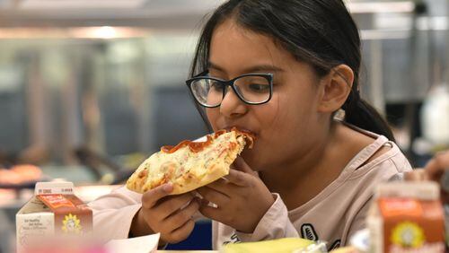 Angelic Ventura, 8, eats a slice of pizza with whole wheat crust for her lunch at Corley Elementary School on Wednesday, Dec. 12, 2018. Agriculture Secretary Sonny Perdue recently announced final rule school-meal guidelines designed to increase local flexibility in implementing nutrition standards for milk, whole grains and sodium. HYOSUB SHIN / HSHIN@AJC.COM