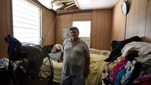 In this Oct. 19 photo, Moises Valentin poses in his home damaged by Hurricane Maria, where the U.S. Army Corps of Engineers built him a temporary roof, in San Juan, Puerto Rico. Valentin, 63, has been recycling cans to make ends meet, picking through mountains of stinking, rotten trash. AP/Carlos Giusti