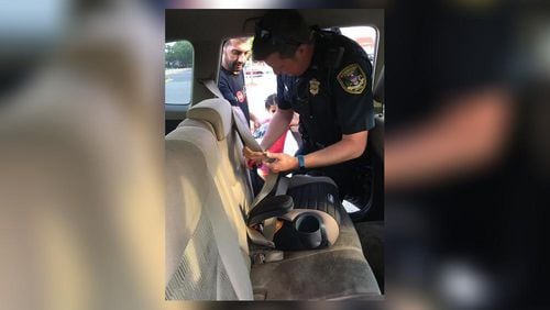 Dunwoody police Officer Jeffrey Leach installs a car seat for a man caught driving without safety equipment for his youngest child. (Credit: Dunwoody Police Department)