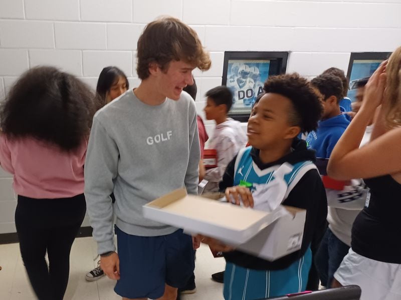 Collin Maher, left, receives thanks from students who received shoes as a result of his efforts. (Photo Courtesy of Bob Pepalis)