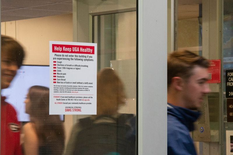 Last month, new residents of the Lipscomb dormitory at UGA exited the building past a sign advising persons experiencing COVID-19 symptoms not to enter. (Julian Alexander for The Atlanta Journal-Constitution)