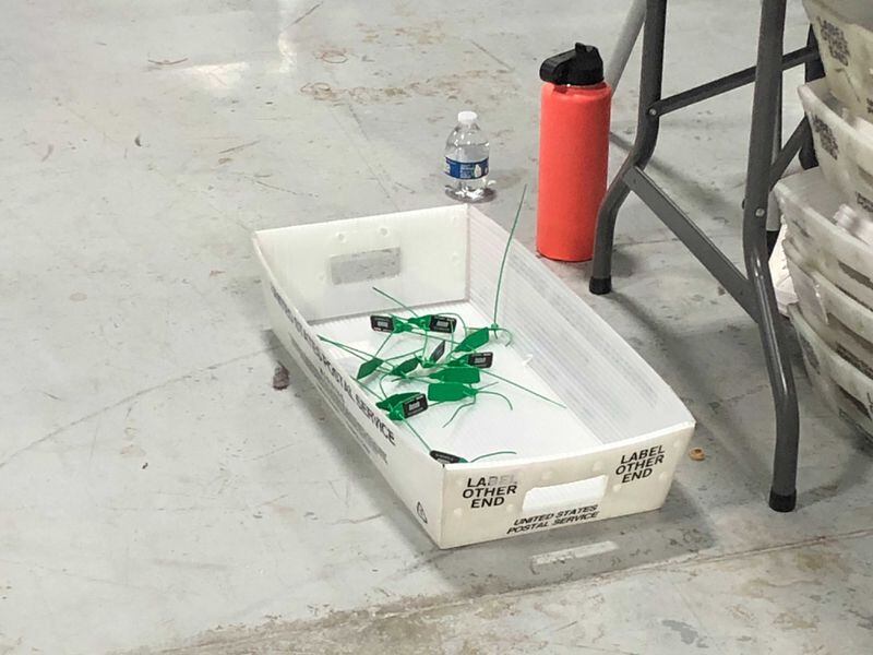 In the Gwinnett County elections office, zip ties that had secured the ballot boxes during lunch are cut discarded as counting is set to resume for the recount. Credit: J. Scott Trubey
