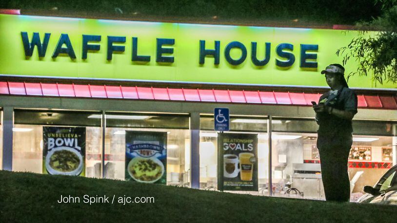 A Waffle House employee stands in the parking lot where a woman was fatally shot on Flat Shoals Parkway in DeKalb County. JOHN SPINK / JSPINK@AJC.COM