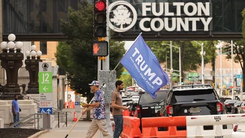 Ian Smith holds a Trump flag as he passes the Fulton County Courthouse on Friday, August 4, 2023. Road closures are expected to begin next week ahead of possible charges against former President Donald Trump from the Fulton County district attorney’s office. (Natrice Miller/ Natrice.miller@ajc.com)
