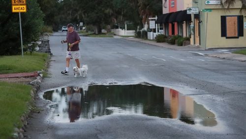 St. Mary resident John Bell takes his dog Austin Healey for a walk Thursday morning after Hurricane Dorian passed Georgia’s southernmost coastal city late Wednesday. The city was mostly quiet after suffering minor wind damage and flooding. Curtis Compton/ccompton@ajc.com