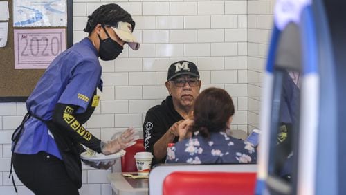 Now that stay-at-home orders have been lifted in Georgia, restaurant servers like Waffle House’s Miss D (left) are donning masks and gloves to protect their patrons. JOHN SPINK / JSPINK@AJC.COM