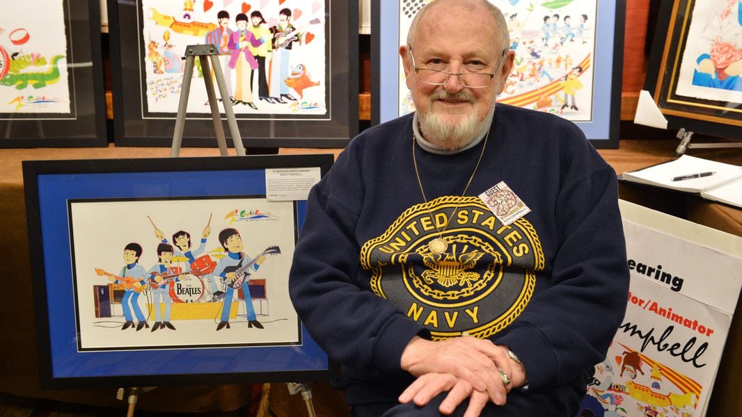 Artist Ron Campbell poses with some of his famous cartoon works.