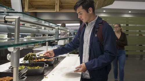 Freshman Will Theodore grabs sauteed spinach and kale from the Stem to Root food bar at the Dobbs Common Table dining hall in the new student center at Emory University. (ALYSSA POINTER / AJC)