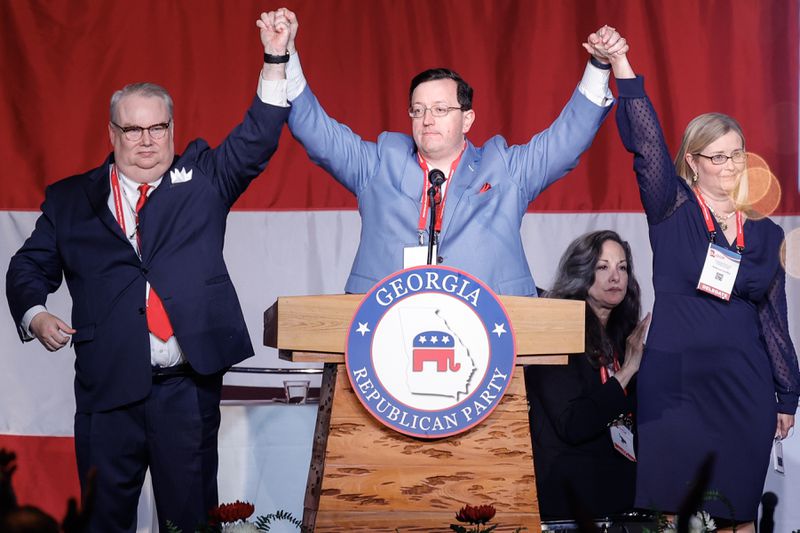 Georgia Republican Party Chairman candidates Dennis Fucch (left) and Rebecca Yardley (right) hold hands with newly appointed chairman Joshua McKoon (center) during the GOP Convention on Saturday, June 10, 2023. (Natrice Miller/natrice.miller@ajc.com)