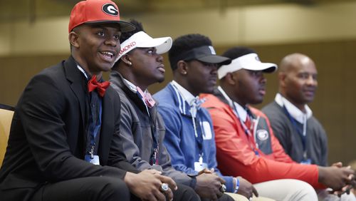 Pace Academy players are arrayed in the colors of their chosen schools during last year's National Signing Day. Trey Blount, in the Georgia hat, is in the foreground. (DAVID BARNES / DAVID.BARNES@AJC.COM)