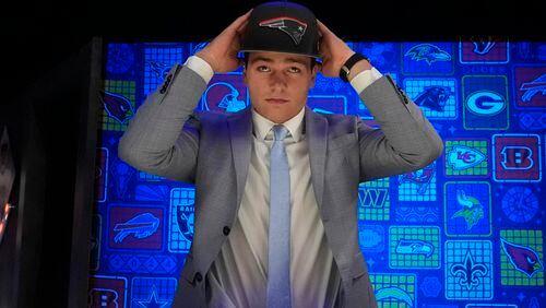 North Carolina quarterback Drake Maye puts on a hat after being chosen by the New England Patriots with the third overall pick during the first round of the NFL football draft, Thursday, April 25, 2024, in Detroit. (AP Photo/Jeff Roberson)