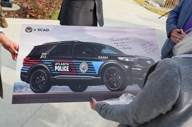 SCAD students hold a poster showing the design of new Atlanta Police Department patrol cars in Atlanta on Wednesday, November 2, 2022. SCAD students created the design. (Arvin Temkar / arvin.temkar@ajc.com)