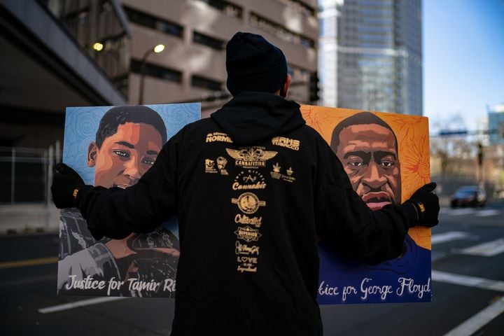 A man hold pictures of George Floyd and Tamir Rice outside the Hennepin Country Government Center in Minneapolis, Minn., on Tuesday, April 20, 2021, where the Derek Chauvin trial is taking place. (Amr Alfiky/The New York Times)