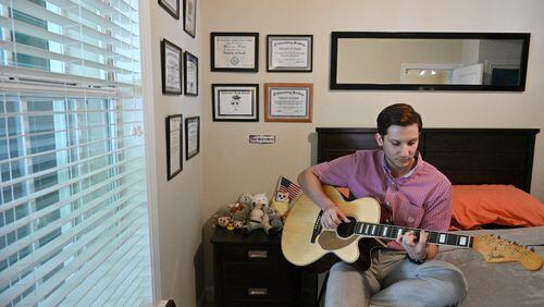 Abdallah Al-Obaidi, who is an Emory student and an Iraqi refugee, plays his guitar at his apartment in Decatur on Thursday, June 17, 2021. (Hyosub Shin / Hyosub.Shin@ajc.com)
