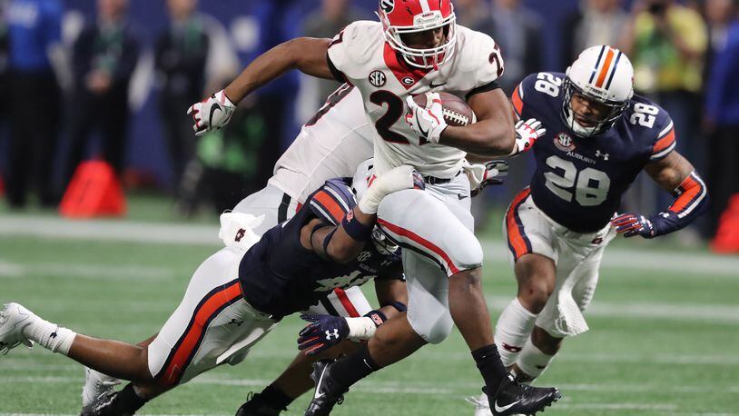 Nick Chubb  high-steps past Auburn defenders Darrell Williams (l) and Tray Matthews (28) during the second half of the SEC Championshipgame Saturday.