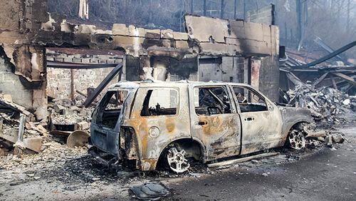 A scorched vehicle sits next to a burned out building in Gatlinburg, Tenn., on Tuesday, Nov. 29, 2016. The fatal fires swept over the tourist town the night before, causing widespread damage. (AP Photo/Erik Schelzig)