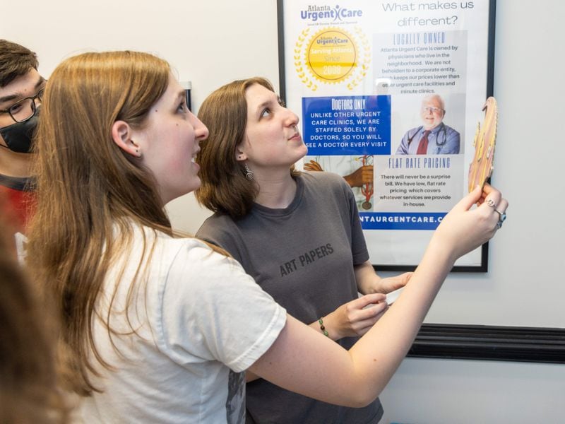 Lakeside High School Art Club member Chloe Toll & her sister Lily try to decide where to hang a sea creatures on a blue wall of a pediatric exam room at the Atlanta Urgent Care nearby. PHIL SKINNER FOR THE ATLANTA JOURNAL-CONSTITUTION