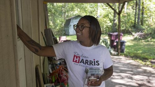 Republican DeAnna Harris places a campaign flyer in the door of a house along Leatherleaf Drive Southwest in Marietta. Harris, who is running for a state House seat in a district where voters favored Hillary Clinton over Donald Trump in the 2016 presidential election, says she tries to focus conversations with voters on what’s happening in the district, not in the White House. “When people come at me with the whole Trump conversation, I have to bring them back,” she said. (ALYSSA POINTER/ALYSSA.POINTER@AJC.COM)