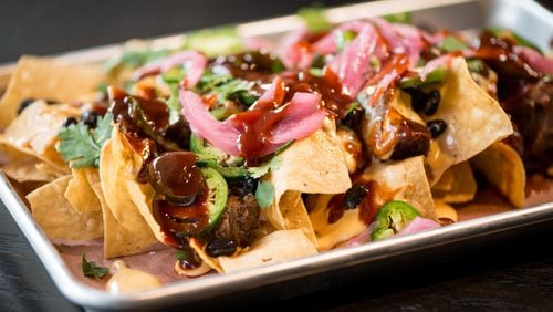 BBQ Nachos, chips and cheese covered with brisket, jalapenos, pickled onions, black beans, cilantro, and BBQ sauce. Photo credit- Mia Yakel.