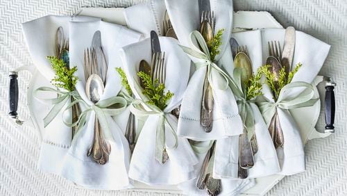 Sprigs of greenery and small satin ribbons spruce up place settings, with no napkin-folding expertise required. Greg DuPree for The Atlanta Journal-Constitution