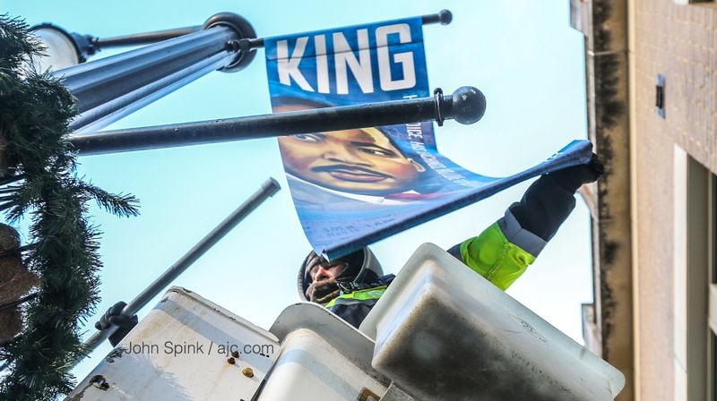 Wright Brown Electric Company’s Keith Bentley tried to stay warm Wednesday morning as he removed MLK banners on Auburn Avenue. JOHN SPINK / JSPINK@AJC.COM