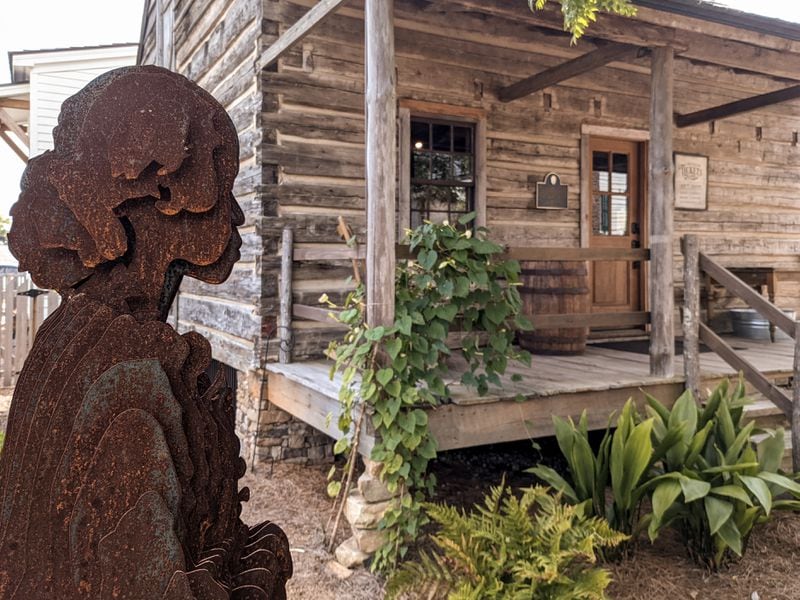 A sculpture outside a cabin at the William Root House Museum in Marietta, Georgia, depicts the life of enslaved people in the 1850s. Cobb Landmarks