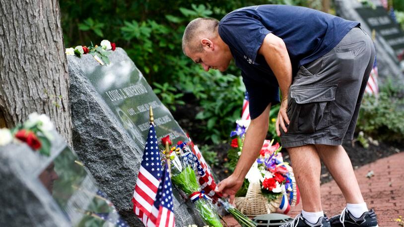 Chris Petraglia of Middletown puts flowers at the memorial stone of Louis J. Minervino while visiting the Middletown World Trade Center Memorial Gardens on the 10th anniversary of the 9/11 terror attacks, Sunday Sept. 11, 2011 in Middletown, NJ.  (AP Photo/Joe Epstein)