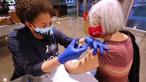 Dr. Lynn Paxton (left), District Health Director of  the Fulton County Board of Health, gives a Pfizer vaccine to Karen Schaefer at Mercedes-Benz Stadium on Wednesday.  Curtis Compton / Curtis.Compton@ajc.com”