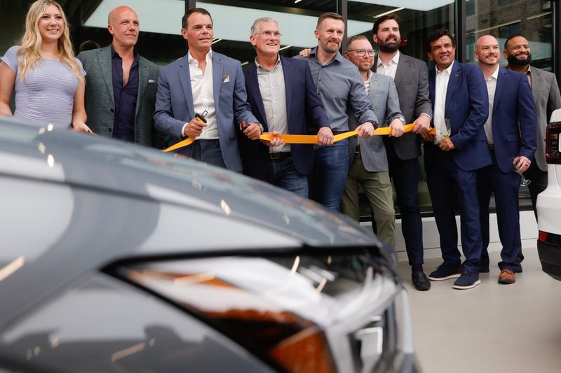 Polestar electric vehicle employees unbuckle a golden seat belt as a substitute for a ribbon cutting to celebrate the company’s first showroom in Atlanta at The Battery on Tuesday, June 20, 2023. (Natrice Miller/ Natrice.miller@ajc.com)
