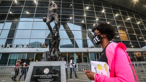 Ashley Nealy makes her way past the statue of Dominique Wilkins as she waited to vote on Monday, Oct. 12, 2020 at State Farm Arena in downtown Atlanta. Eager Georgia voters swarmed to polling places Monday morning, waiting in lines created by high turnout and technical problems at the start of three weeks of early voting before Election Day. (John Spink / John.Spink@ajc.com)