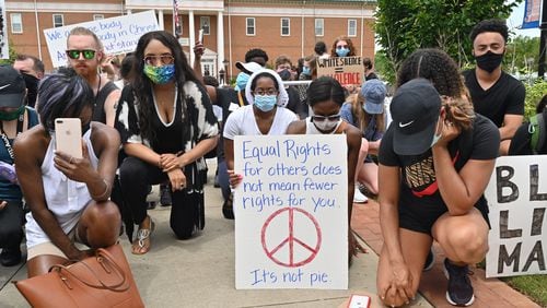 Demonstrators kneel in a moment of silence outside the Forsyth County courthouse in Cumming during a peaceful protest for unity and equality in June 2020. Efforts continue in the county to make sure its troubled past, which included a cleansing of Black residents more than a century ago, isn't forgotten. (Hyosub Shin / Hyosub.Shin@ajc.com)