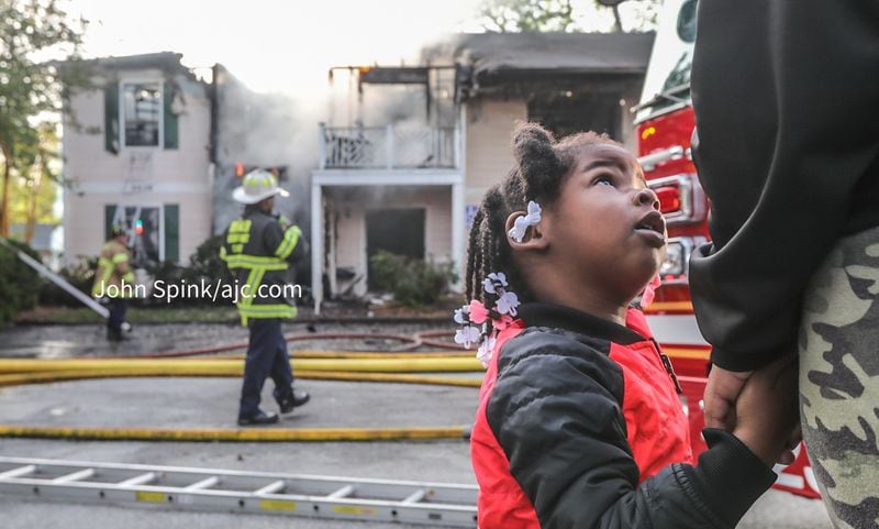 Mariah Peterson, 3, and her mother Breonna Clark watch as their neighbors' building burns at the Northlake Manor Condominiums in Tucker. 