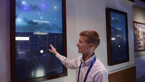 Miles Clark of Carnival Corp. demonstrates the Ocean Compass interface before CES International, Tuesday, Jan. 3, 2017, in Las Vegas. The linchpin of the concierge technology is a medallion the size of a quarter that passengers carry with them. The medallion uses wireless technologies to communicate with sensors placed around the ship and allows them to interact with displays around the ship or with crew members. (AP Photo/John Locher)