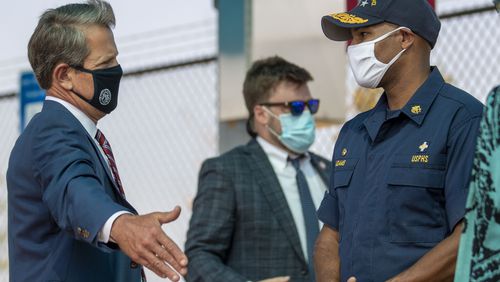 08/10/2020 - College Park, Georgia - Gov. Brian Kemp (left) speaks with U.S. Surgeon General Vice Admiral Jerome M. Adams before the start of a press conference at a drive-thru COVID-19 testing clinic located in a Hartsfield-Jackson International Airport paid parking facility in College Park, Monday, August 10, 2020. Both GOv. Kemp and Vice Admiral Adams encouraged Georgians to where a mask to combat the spread of COVID-19.  (ALYSSA POINTER / ALYSSA.POINTER@AJC.COM)